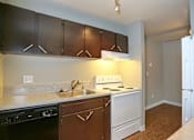 Thumbnail 8 of 8 - A kitchen with brown cabinets and white appliances.
