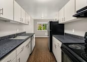 Thumbnail 4 of 8 - A kitchen with black appliances and white cabinets.