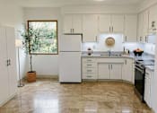 Thumbnail 3 of 8 - A kitchen with white appliances and cabinets.