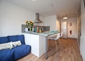 Thumbnail 6 of 8 - a kitchen and dining area with a blue couch and a bar with stools