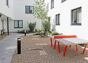 Thumbnail 14 of 16 - A white building with a red table in front of it.
