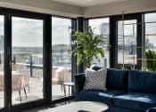 Thumbnail 7 of 19 - a living room with a blue couch and a balcony with a city view