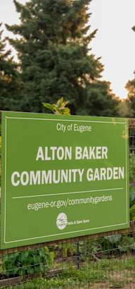 a sign for the community garden on a fence