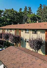Apartment complex with a brown roof and trees in the background.