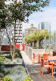 A rooftop patio with orange chairs and tables.