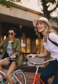 two women riding bikes down the street