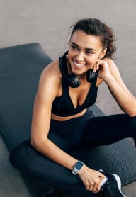 a woman sitting on a gym floor with a workout ball and headphones