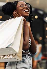 A woman is holding a shopping bag and smiling.
