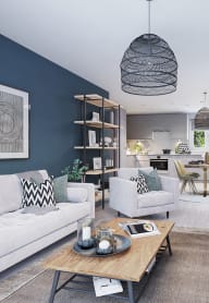 an open plan living room and kitchen with a white sofa and chairs and a glass coffee table