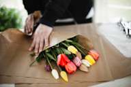a person wrapping a bouquet of tulips in a paper bag