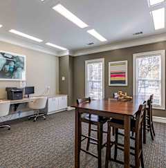 A living room with a grey couch, a glass coffee table, and a painting on the wall at Austin Chase Apartments, Macon, GA