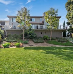 View from behind the property. Fenced area with grass and trees for pets to roam