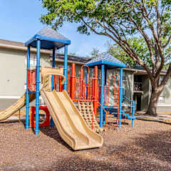 A playground with a blue and orange slide in front of a building.