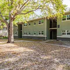 A green building with a tree in front of it.