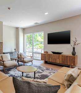 A living room with a brown couch and a flat screen TV mounted on the wall.