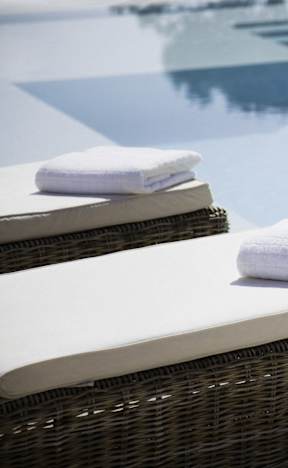 Towels on a wicker chair by a pool.