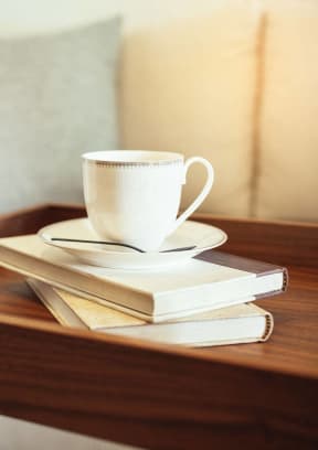 a coffee cup and books on a tray on a couch