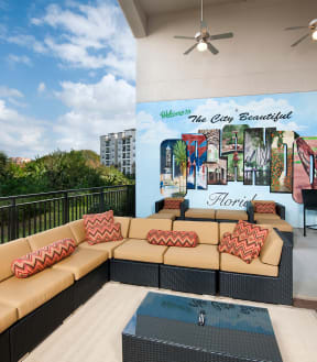 a patio with couches and a coffee table in front of a mural