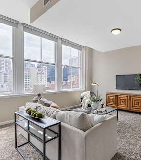 A living room with a grey couch, a black coffee table, a wooden cabinet, and a television.