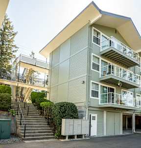 A modern apartment building with a green tree in front.