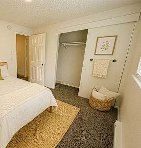 A bedroom with a bed, nightstand, and a basket on the floor.