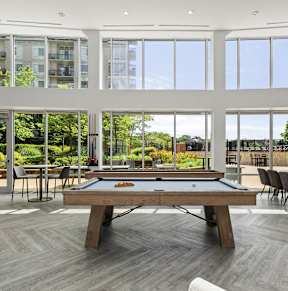 a pool table in a living room with large windows