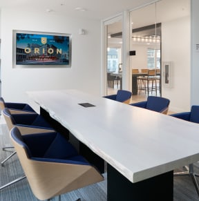 a conference room with a long white table and blue chairs