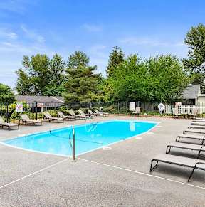 A swimming pool surrounded by trees and a building.