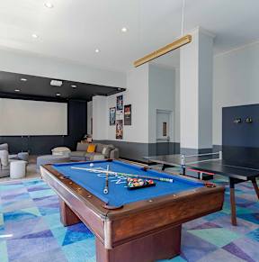 A pool table is in the middle of a room with a blue carpet.