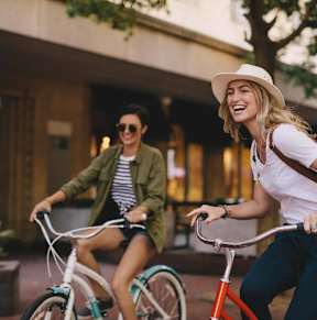 two women riding bikes down the street