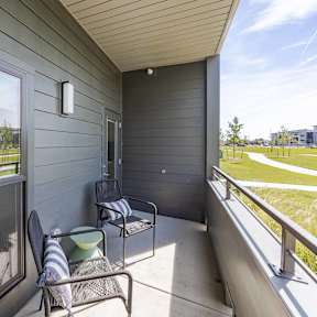 A balcony with a chair and a table with a striped towel on it.