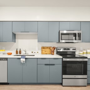 a kitchen with gray cabinets and a stainless steel refrigerator