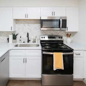 A kitchen with white cabinets and a black stove top oven.at Century Apartments, Tennessee