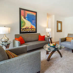 A living room with a grey couch, a coffee table, and a painting on the wall.