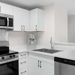 A modern kitchen with white cabinets and appliances.