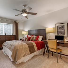 A bedroom with a bed, desk, and chair.