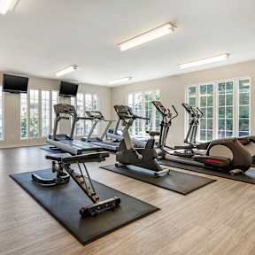 A spacious gym with a variety of equipment including treadmills, stationary bikes, and weight machines.