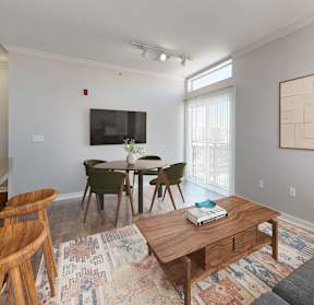 A living room with a grey couch, a wooden coffee table, and a TV on the wall.
