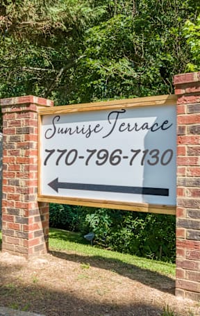 A sign for Surprise Terrace General Property Management stands in front of a house.