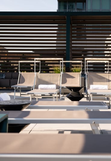 a row of lounge chairs on a patio with a building in the background