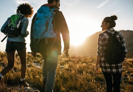 a group of people hiking up a hill at sunset
