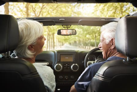 an older couple sitting in their car looking at each other