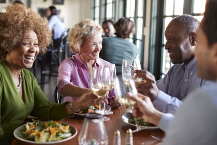 a group of people sitting at a table eating and drinking wine