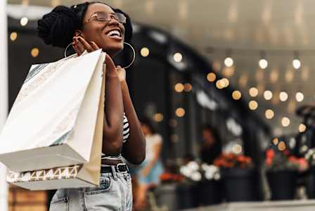 A woman is holding a shopping bag and smiling.