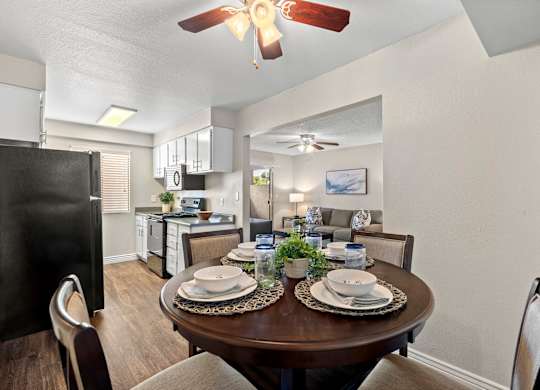 A dining room with a table set for two and a ceiling fan.