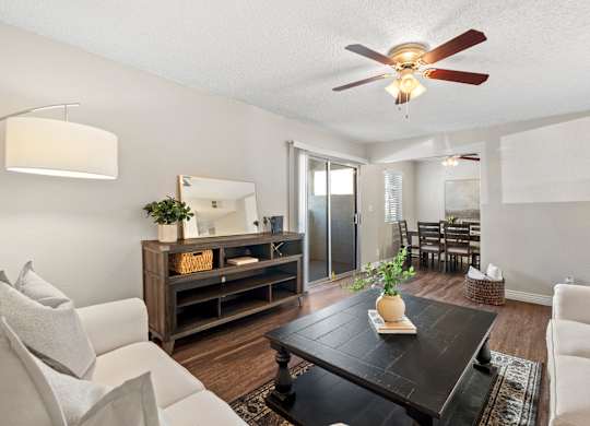 A living room with a white couch, a wooden coffee table, and a ceiling fan.