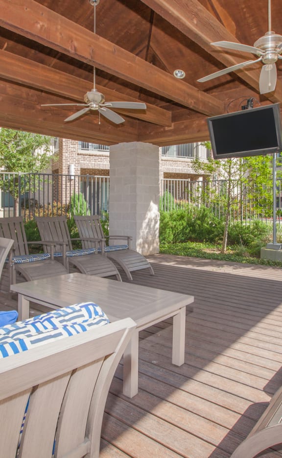 a covered patio with couches and a tv at Ovation at Lewisville Apartments, Texas , 75067