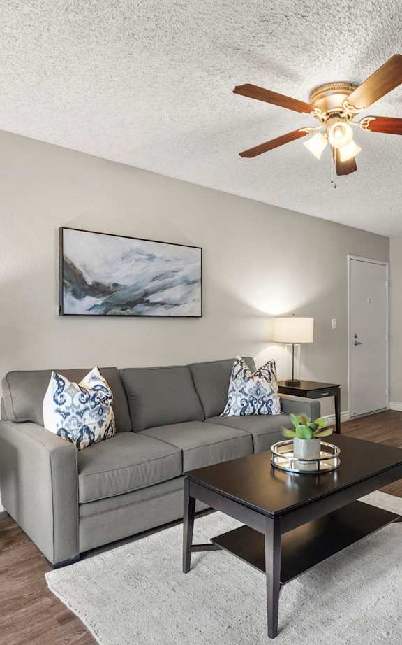 A living room with a blue couch and orange pillows.