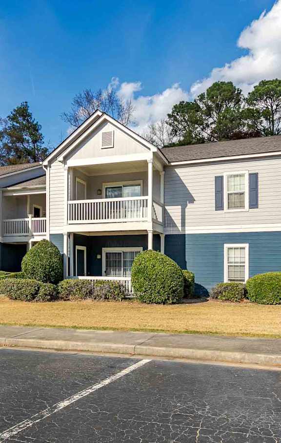 A green house with a balcony and a tree in front at Austin Chase Apartments, Macon