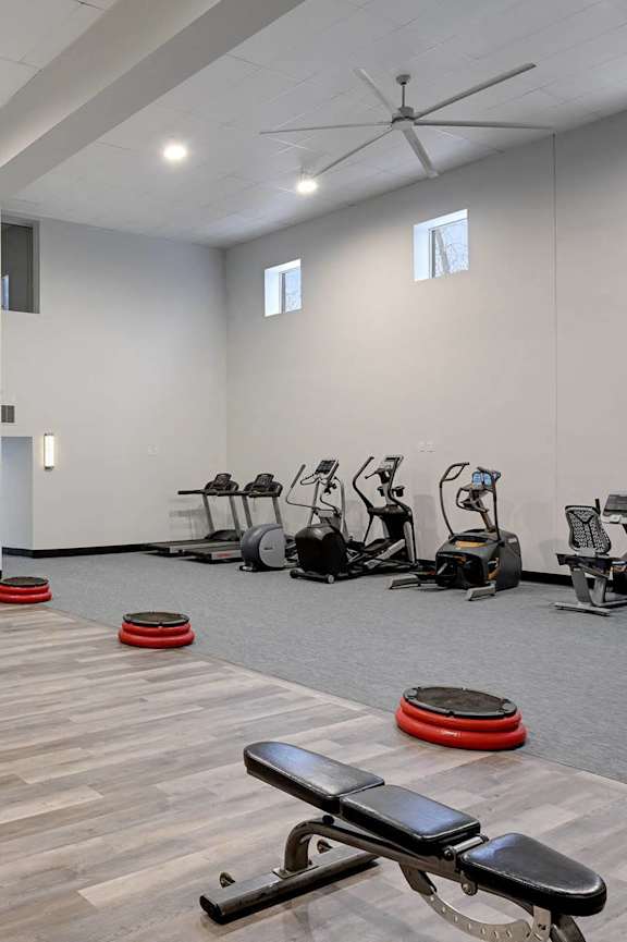 A gym with a variety of equipment including treadmills, weights, and exercise machines.